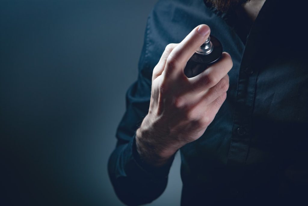 Man spraying perfume on his hand. Close up of male hands.